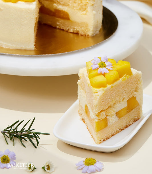 Layered mango mousse cake with fresh diced mango, light sponge, and edible flowers on white cake stand