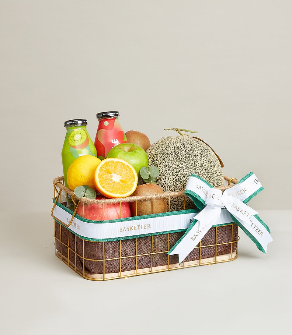 Premium fresh fruit gift basket with juices, apples, kiwis, citrus, and cantaloupe in gold-tone wire basket