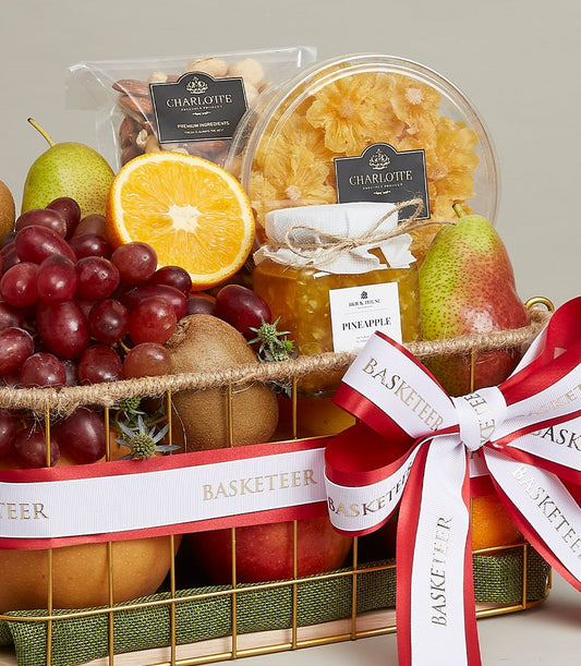 Gold mesh wellness fruit basket with fresh grapes, pears, kiwis, premium nuts, dried pineapple, and gourmet jam