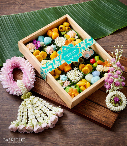 Wooden box of colorful Thai desserts with pink and white flower garlands, teal ribbon, perfect for Songkran New Year
