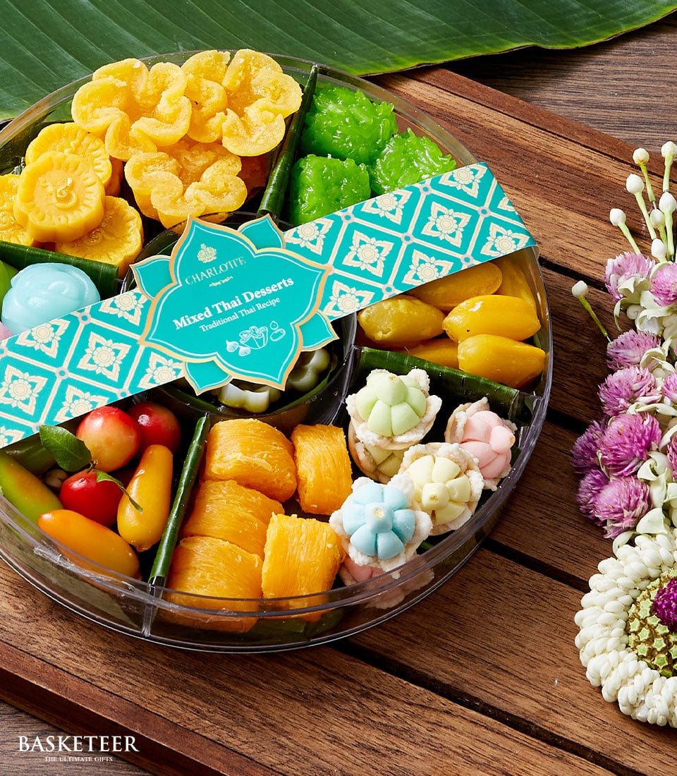 Teal-banded round container of colorful traditional Thai desserts and flower-shaped sweets for Songkran celebration