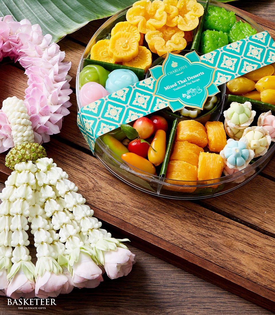 Colorful Thai desserts gift set with jasmine garland, traditional sweets in compartments, Songkran new year celebration