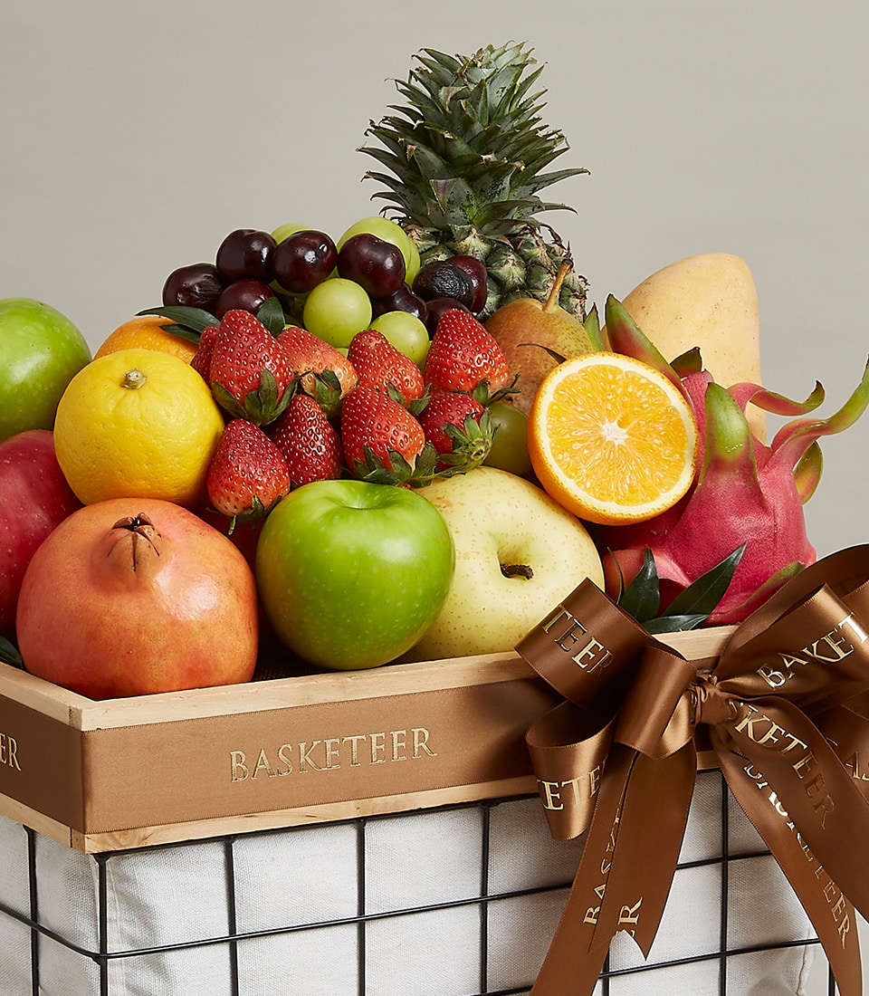 Premium fruit basket with pineapple, apples, mangoes, and berries in handcrafted wooden holder with satin ribbon