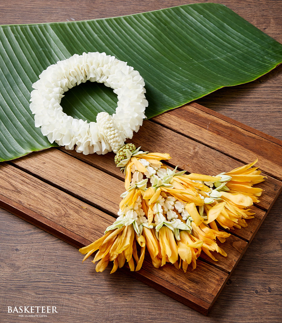 White jasmine phuang malai garland with yellow flower tail on banana leaf, traditional Thai New Year gift