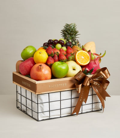 Luxe black wire fruit basket with fresh apples, berries, citrus, and tropical fruits, cream fabric lining, wooden rim, satin