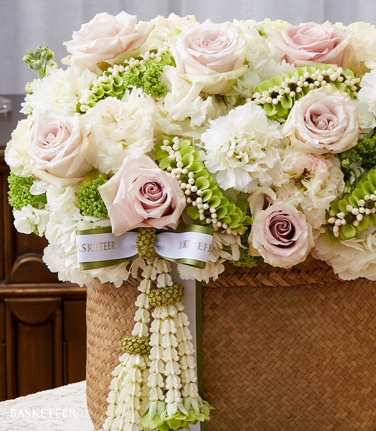 Light pink roses and white carnations in woven basket with Thai floral garland, New Year Songkran gift