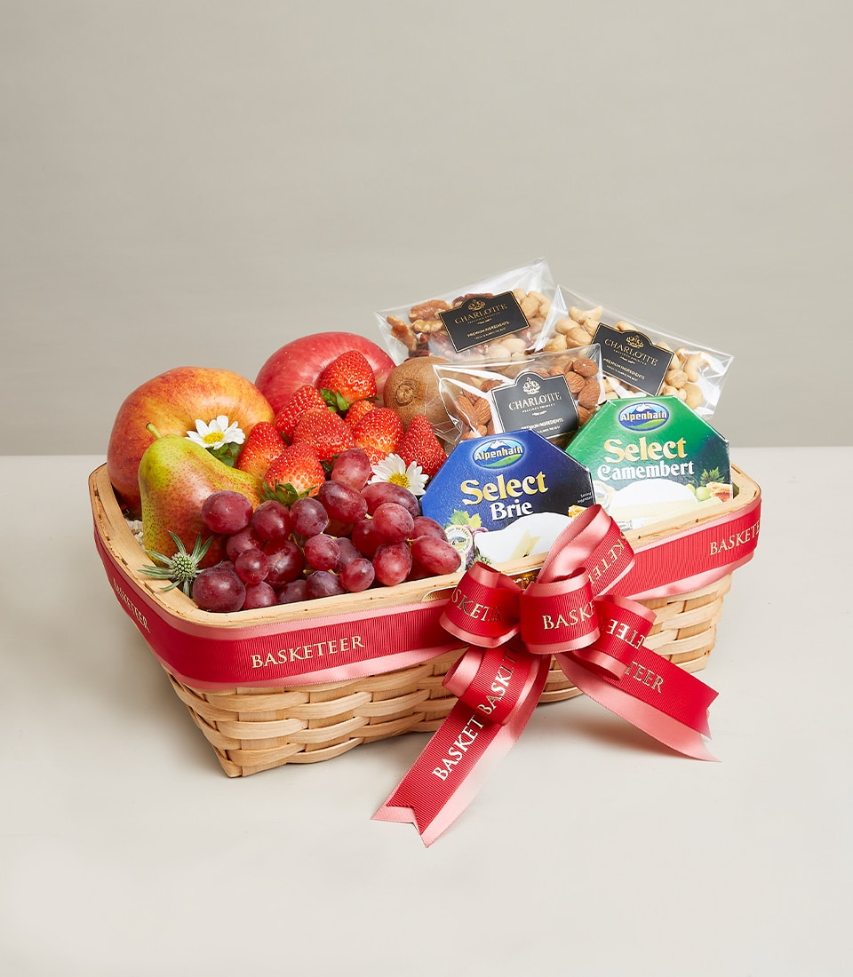 Woven gift basket with fresh fruits, gourmet cheeses, and roasted nuts tied with red ribbon