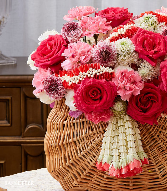 Red and pink roses with Thai phuang malai garlands in wicker basket for Thai New Year Songkran