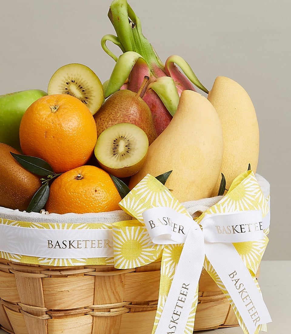 Prestigious gourmet fruit basket with fresh oranges, mangoes, kiwi, pear and dragon fruit in woven wood