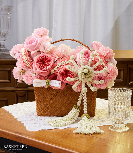 Pink roses in woven Thai basket with jasmine garland, fresh flower arrangement for Songkran New Year