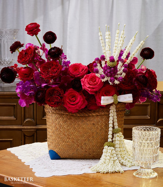 Vibrant red and purple roses with Thai jasmine garland in woven basket, New Year gift arrangement