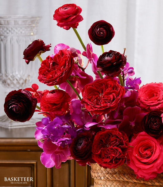 Vibrant red and fuchsia roses with orchids in woven basket, Songkran New Year gift arrangement
