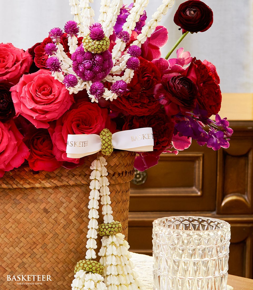Vibrant red and pink roses with purple orchids in woven basket, Thai New Year gift arrangement