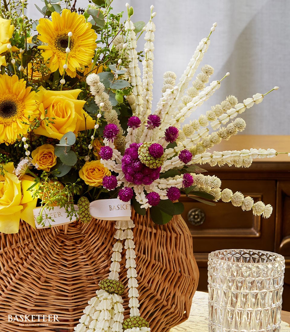 Yellow gerbera daisies and roses in woven basket with jasmine garland for Songkran celebration