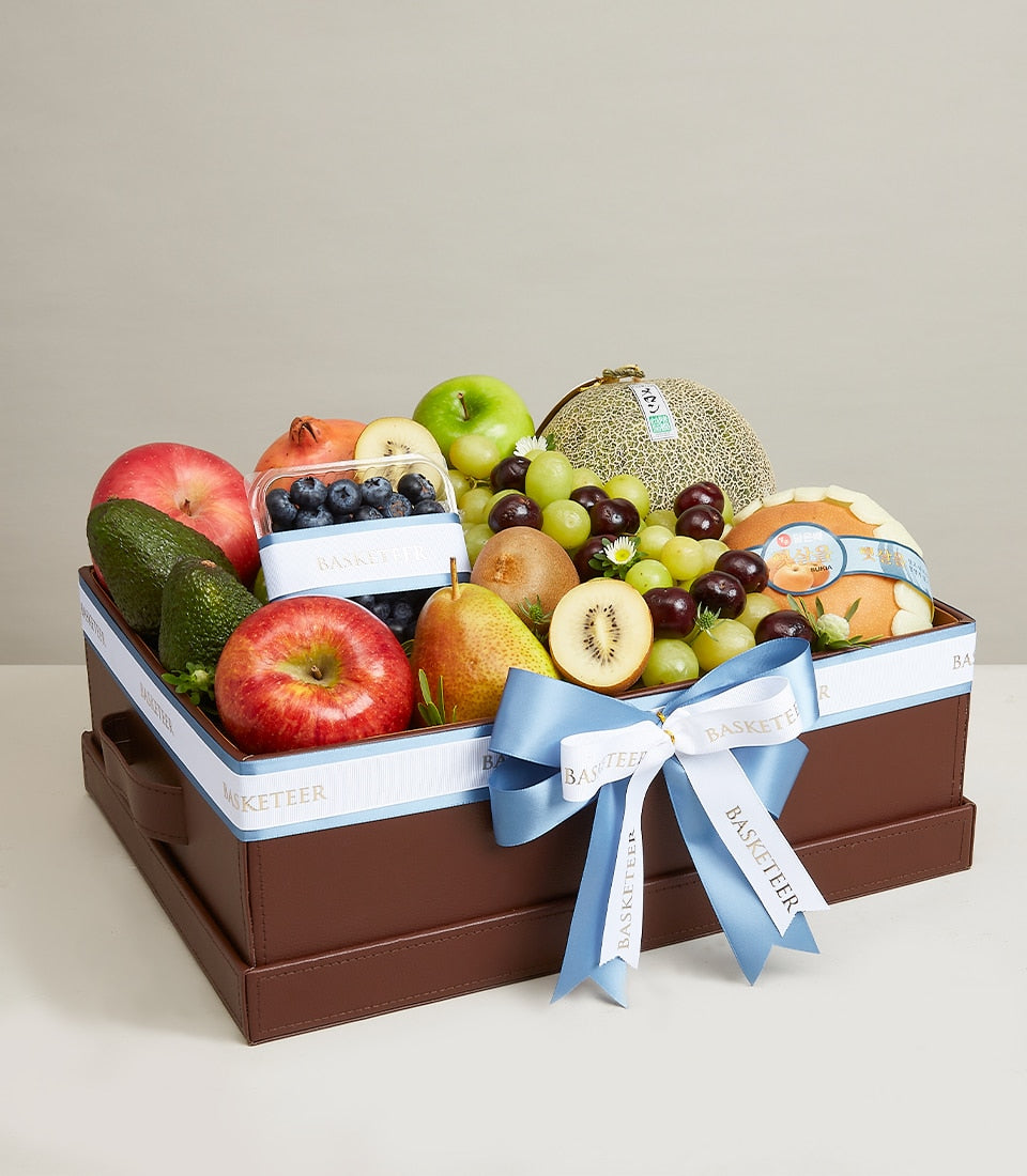 Luxury mixed fruit gift box with red and green apples, grapes, pomegranates, and fresh berries in premium brown packaging