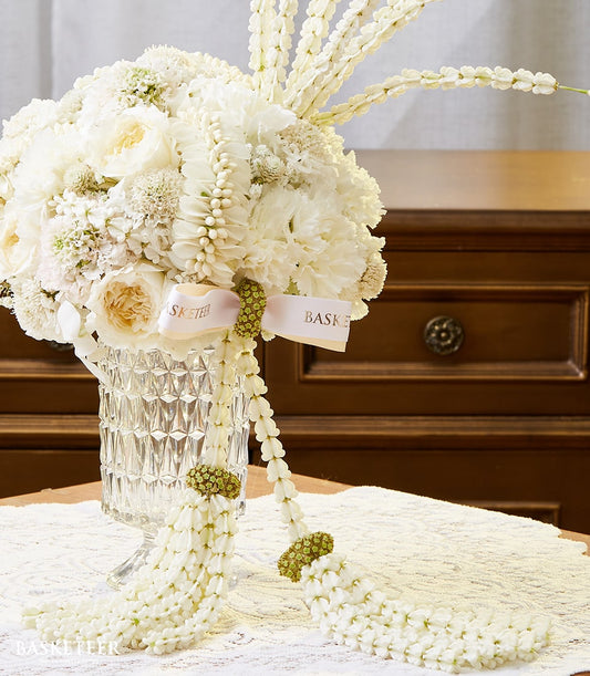 Elegant white rose and carnation arrangement in cut-glass vase with pink ribbon for Songkran celebration