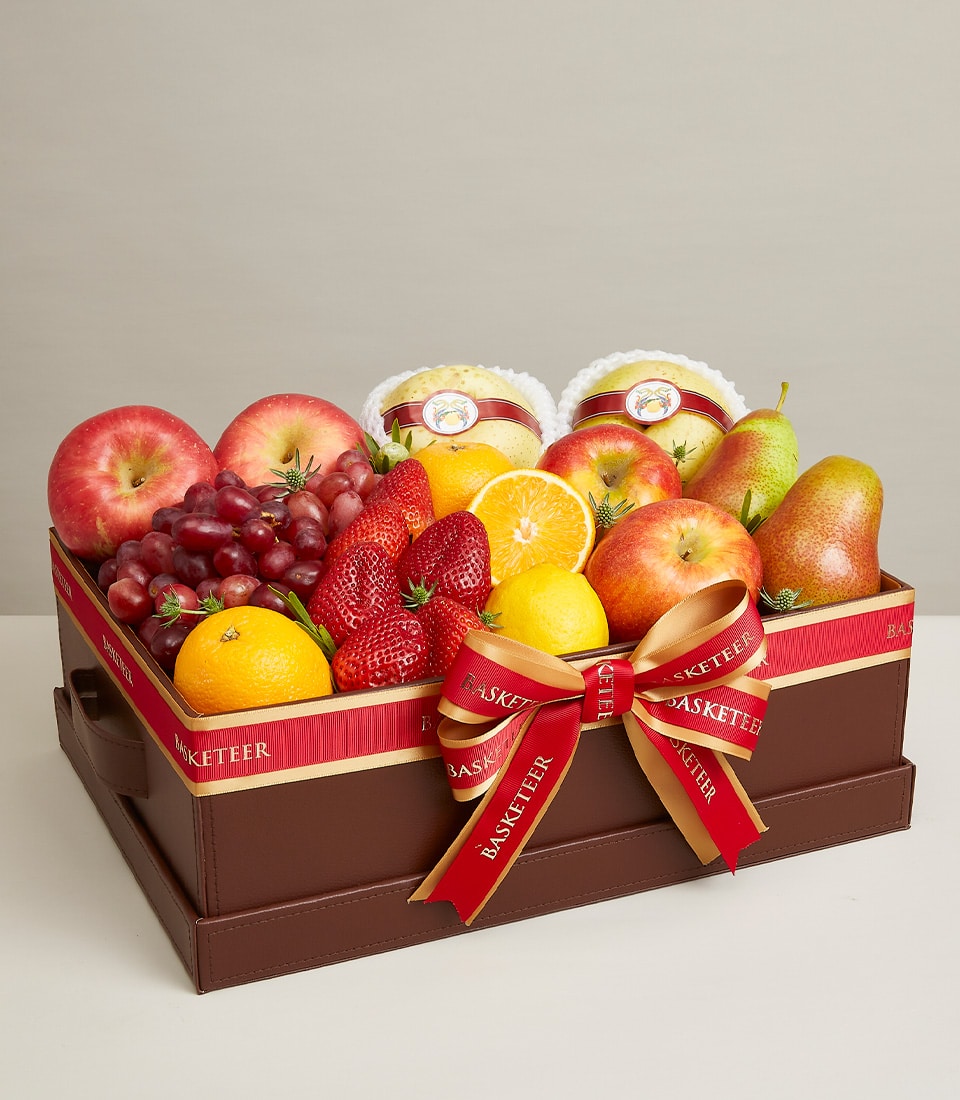 Luxurious mixed fresh fruit gift box with apples, grapes, strawberries, oranges, lemons and pears in dark brown leather box