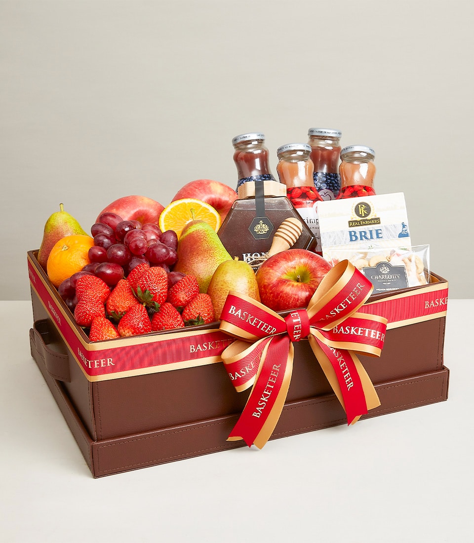 Deluxe fruit and gourmet gift box with fresh strawberries, grapes, apples, brie cheese, honey, and crackers in brown leather