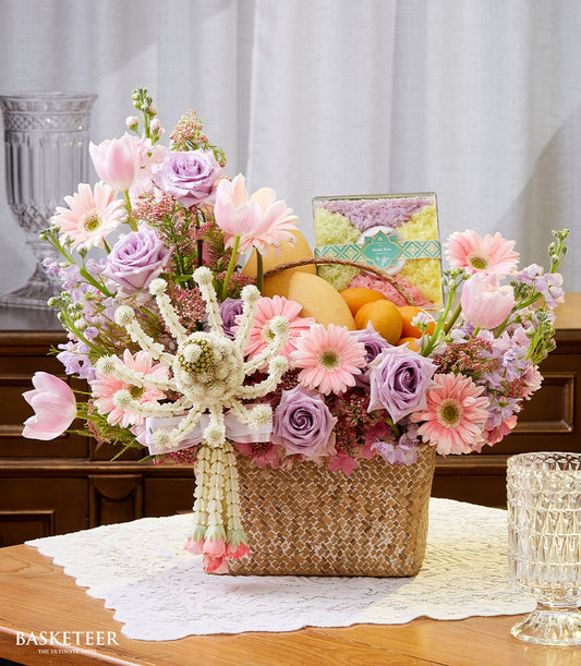 Woven rattan gift basket with fresh pink and purple flowers, yellow mangoes, and colorful mango sticky rice for Thai New
