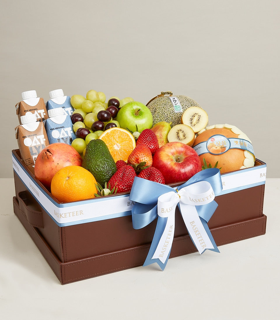 Premium fruit and oat milk gift box with fresh grapes, apples, berries, and Oatly cartons in brown leather hamper