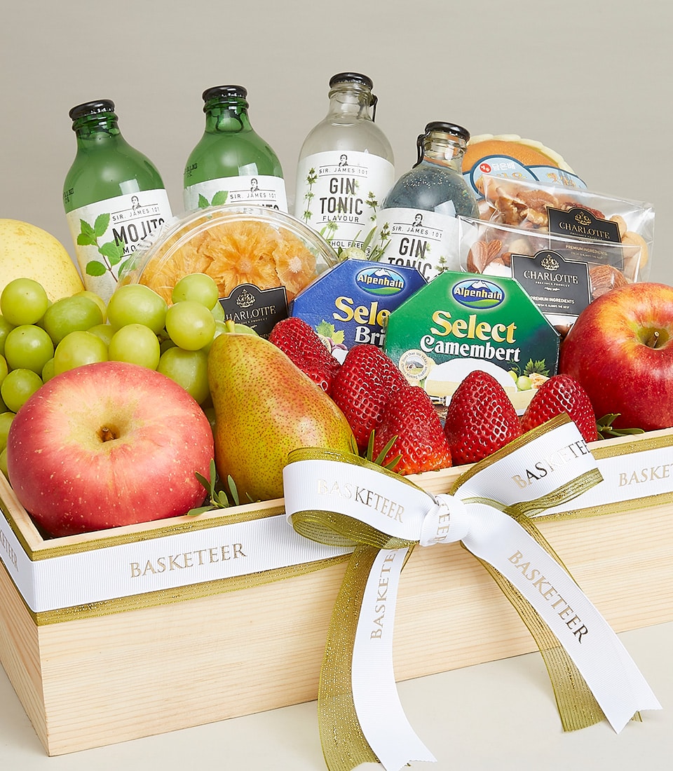 Luxury fruit and cheese gift hamper in wooden crate with fresh strawberries, pear, grapes, Alpenhain cheese, nuts, and