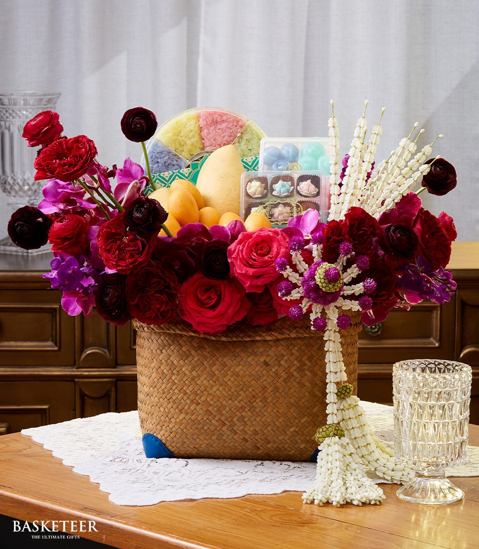 Premium gift basket with red and purple roses, orchids, fresh mangoes, colorful sticky rice, and Thai jasmine garland for