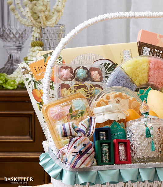 White woven Thai New Year gift basket with dried mangoes, flower pastries, sticky rice, plum jam, and fresh white floral