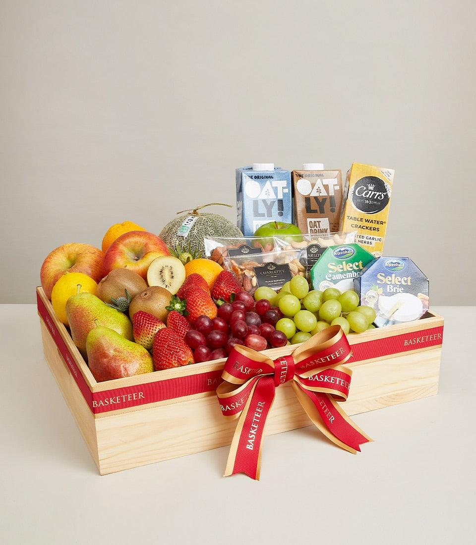 Wooden gift box with fresh fruits, artisan cheeses, crackers, and premium gourmet items tied with red ribbon