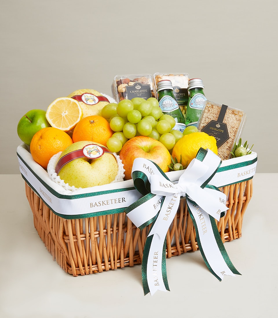 Woven wicker fruit and wellness gift basket with fresh apples, oranges, lemons, grapes, pears, sparkling water, nuts, and