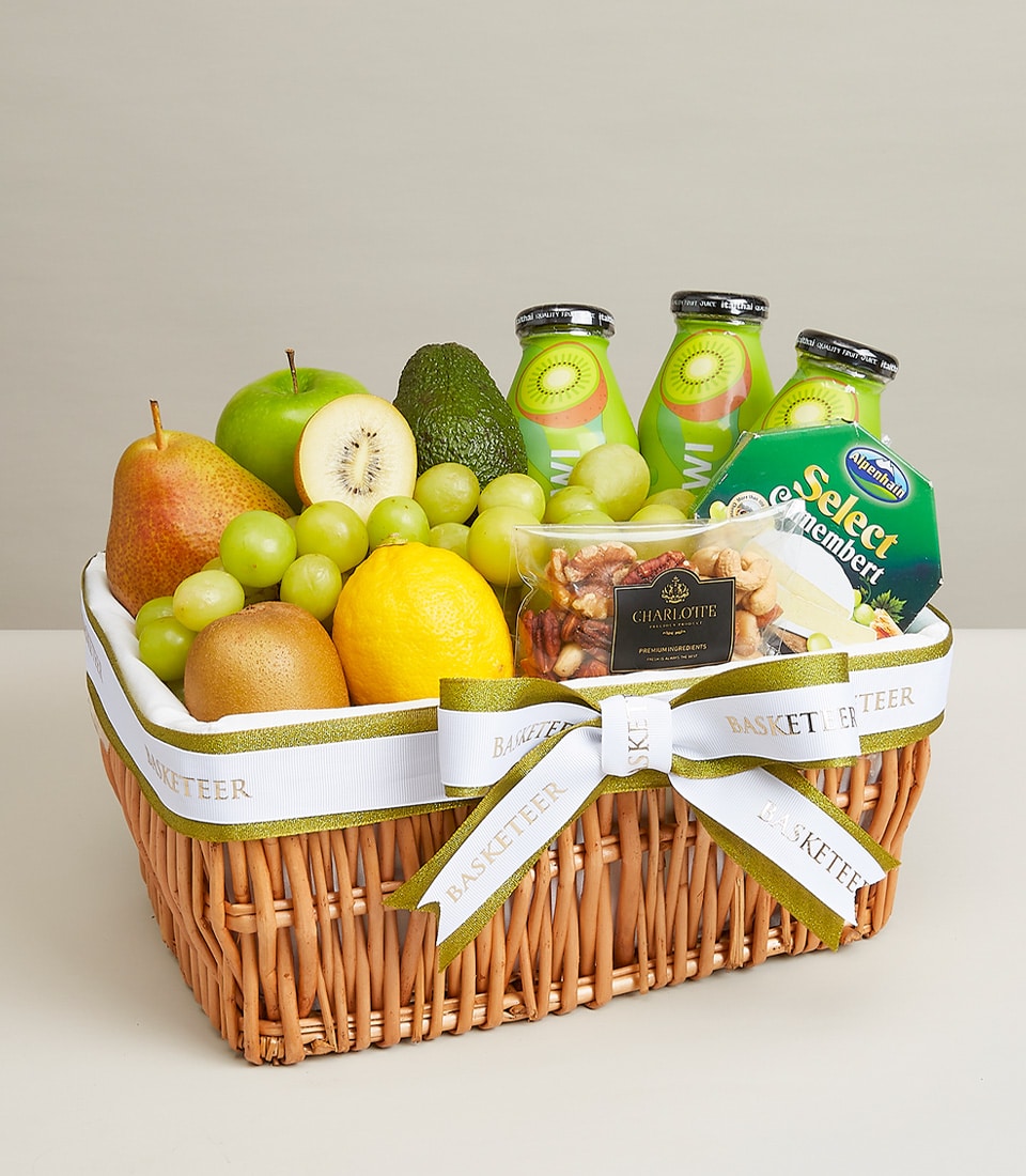 Woven wicker fruit and cheese gift basket with fresh grapes, kiwi, pear, avocado, Camembert, nuts and juice