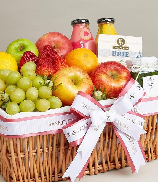 Woven wicker gift basket with fresh fruits, Brie cheese, and gourmet preserves tied with white ribbon