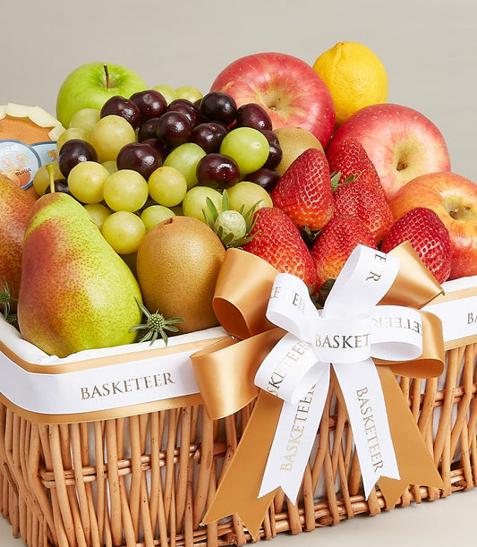 Premium mixed fresh fruit basket in woven wicker with green and red apples, grapes, kiwis, strawberries, pears and lemons