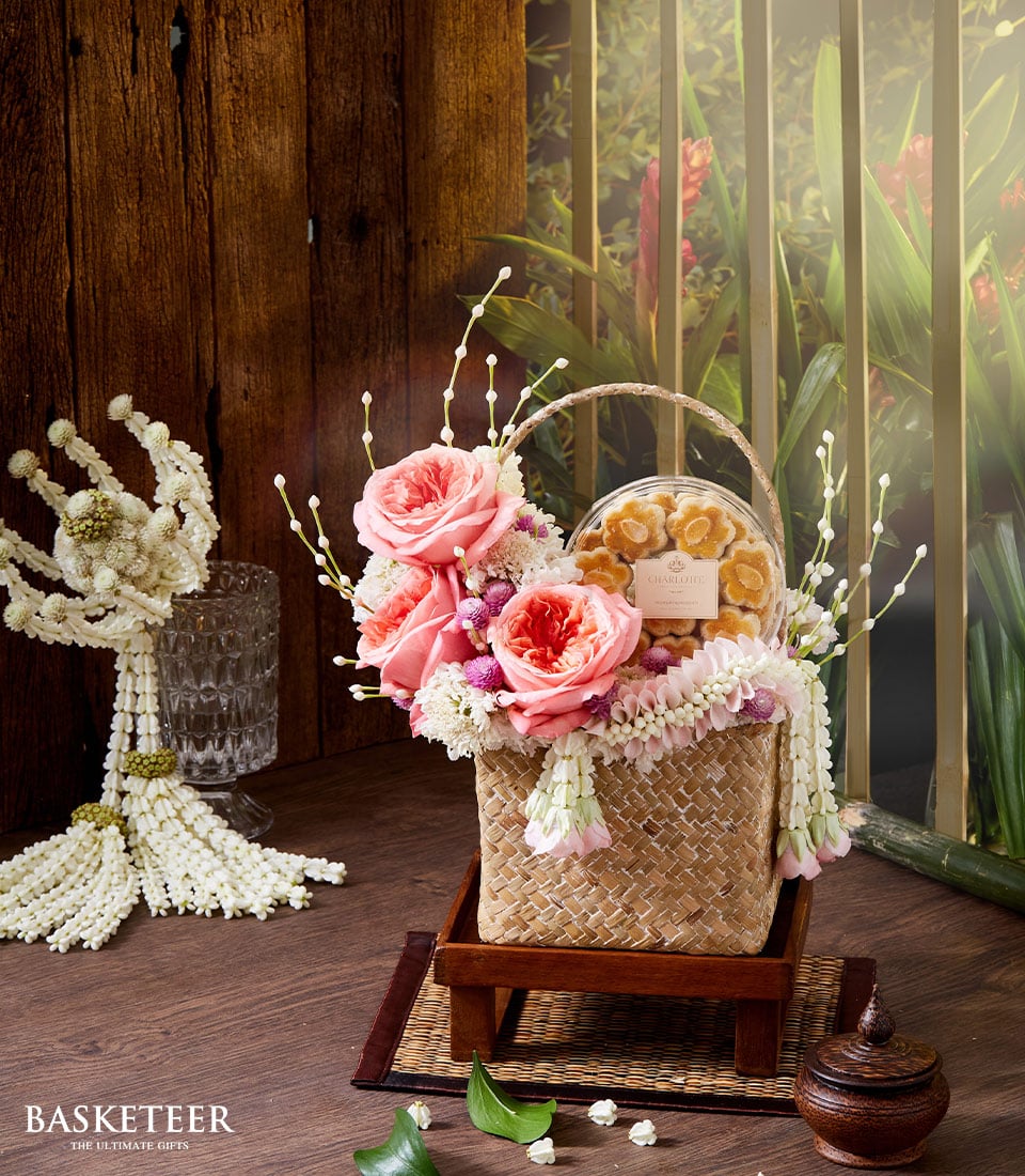 Thai New Year gift basket with pink roses, white blooms, and almond flower cookies