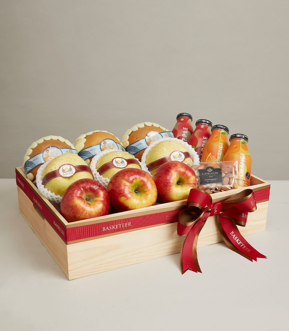 Luxury fruit and wellness gift box with pears, apples, artisan baked goods, fresh juices and almonds in light wood hamper