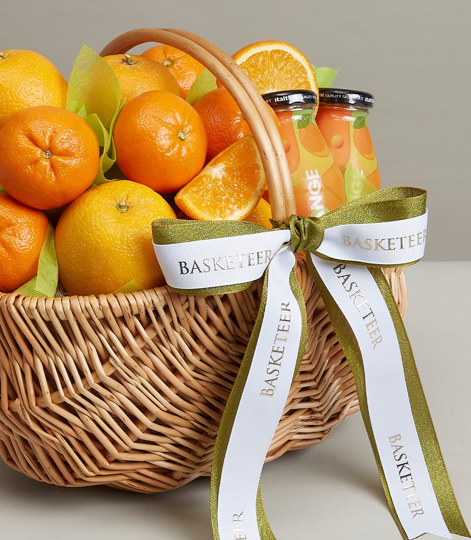 Orange Sensation wicker gift basket with fresh citrus fruits and orange juice bottles, accented with green tissue and