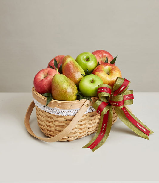 Woven fruit basket with fresh red and green apples, pears, and gold-green ribbon bow