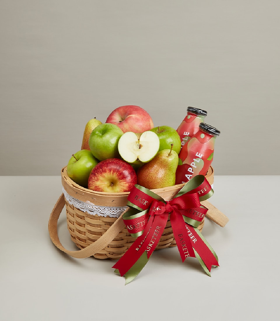 Premium fruit basket with fresh apples, pears, and apple juice in woven wood with white lace trim