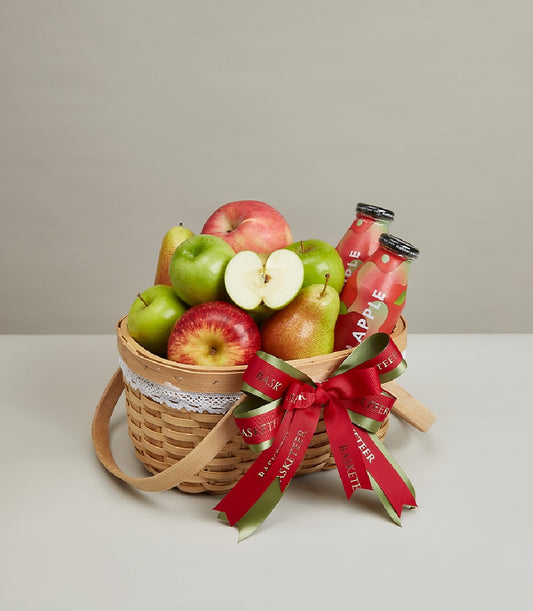 Premium fruit basket with fresh apples, pears, and apple juice in woven wood with white lace trim