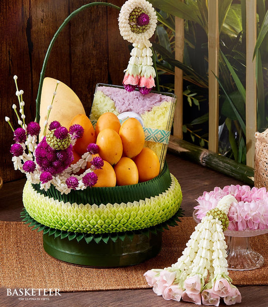 Thai fruit and floral gift basket with mango, sticky rice, and white purple blooms for Songkran