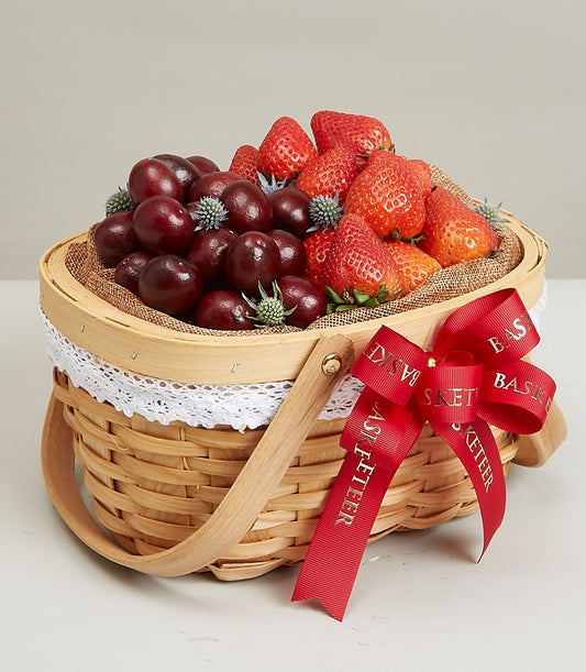 Woven picnic basket filled with fresh strawberries and cherries, white lace trim, red Basketeer ribbon for birthday gifting