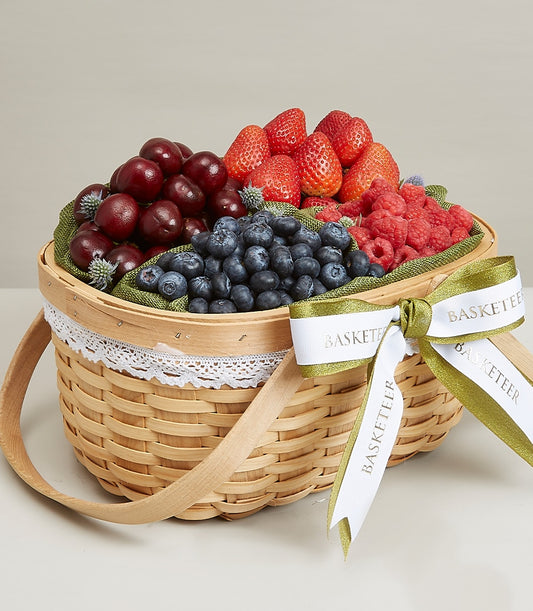 Luxury woven berry fruit basket with fresh cherries, strawberries, blueberries, and raspberries, white lace trim, and gold