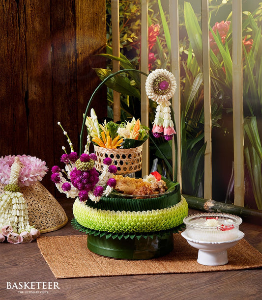 Thai Songkran gift hamper with tiered banana leaf base, carved vegetables, fresh flowers, and traditional offerings on woven