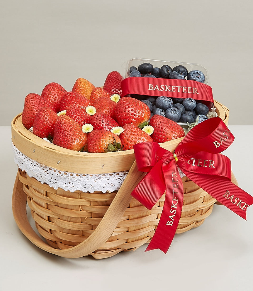 Woven wicker fruit basket with fresh strawberries and blueberries, red ribbon bow, birthday gift