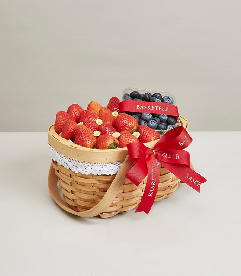 Woven fruit basket with fresh strawberries and blueberries, red satin ribbon bow for birthday gifting