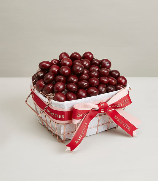 Rose gold wire basket filled with dark red cherries and berries, tied with pink and red Basketeer ribbon