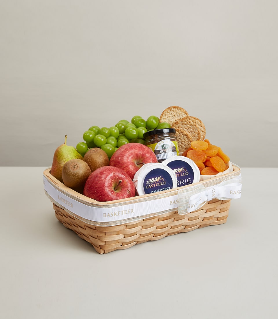 Premium gift basket with fresh fruits, artisan cheeses, and gourmet accompaniments in woven light brown container
