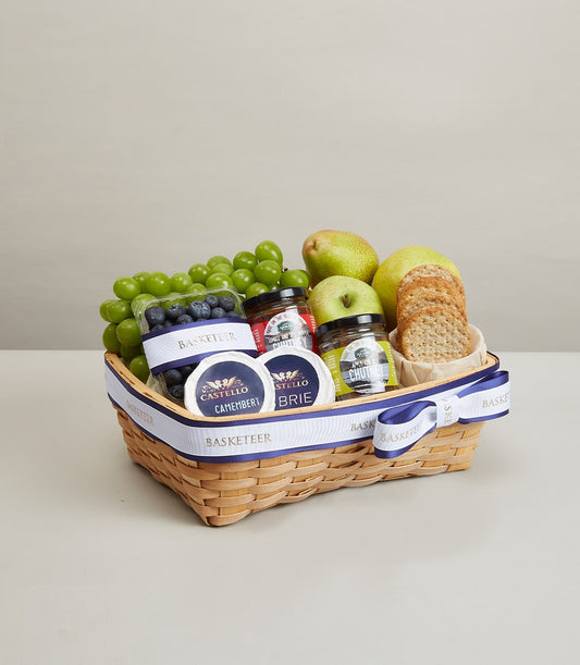 Premium wicker gift basket with fresh grapes, pears, apples, blueberries, artisan cheeses, and gourmet preserves