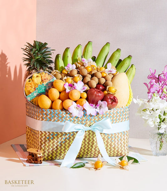 Woven chevron fruit basket with Thai tropical mangoes, pineapple, orchids, and dried fruit snacks