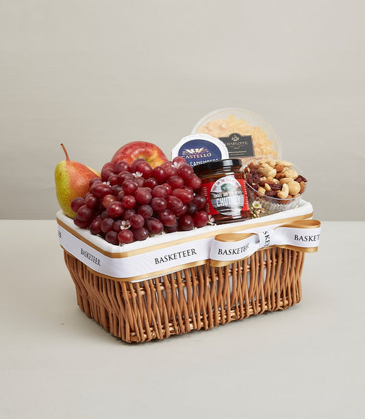 Wicker gift basket filled with fresh apples, pears, grapes, Castello Camembert cheese, and gourmet chutney