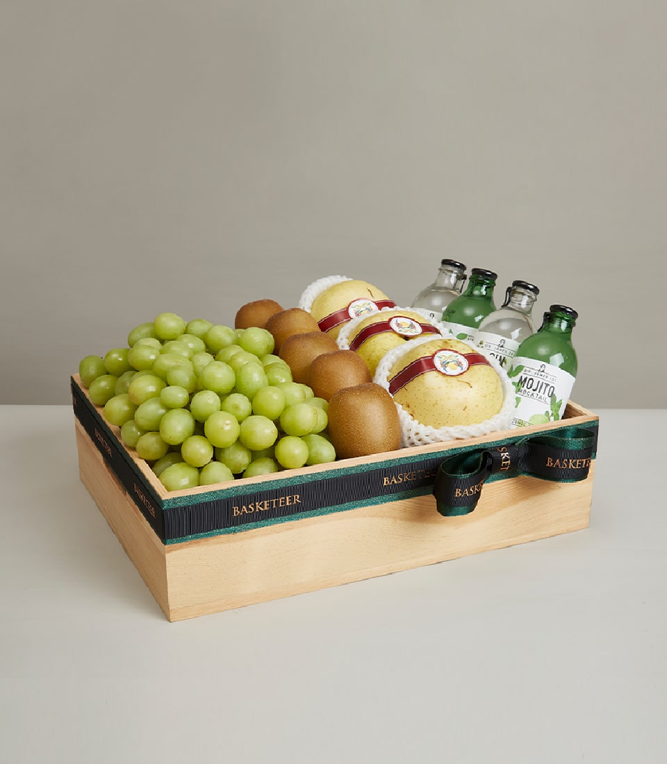Premium wooden gift box with green grapes, pears, kiwis, and artisan mocktail beverages, tied with dark green ribbon